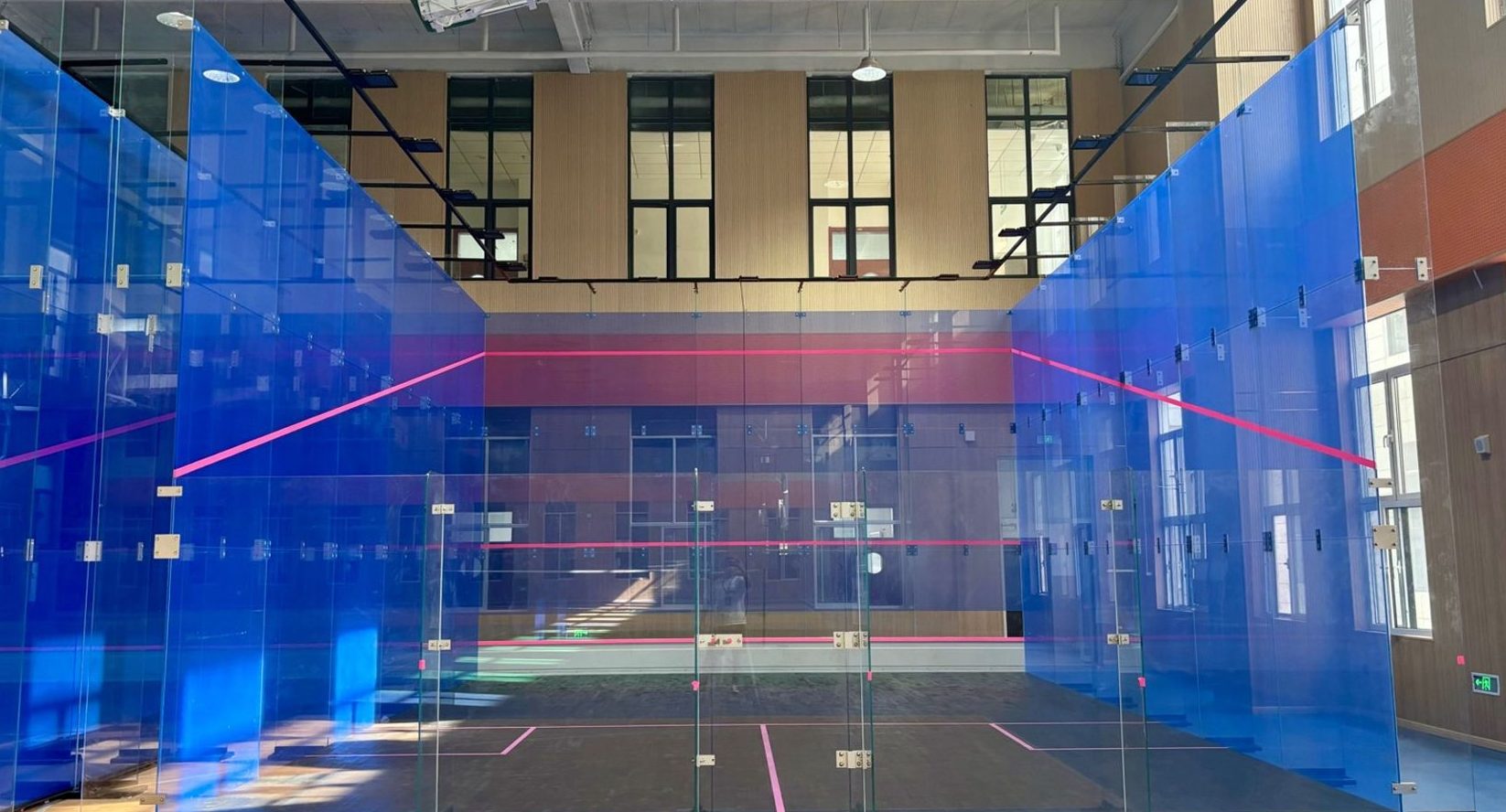 Blue glass squash courts inside a sports hall