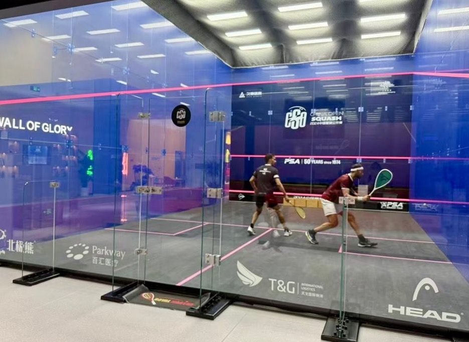 Players on a branded glass court at the 2024 China Squash Open venue