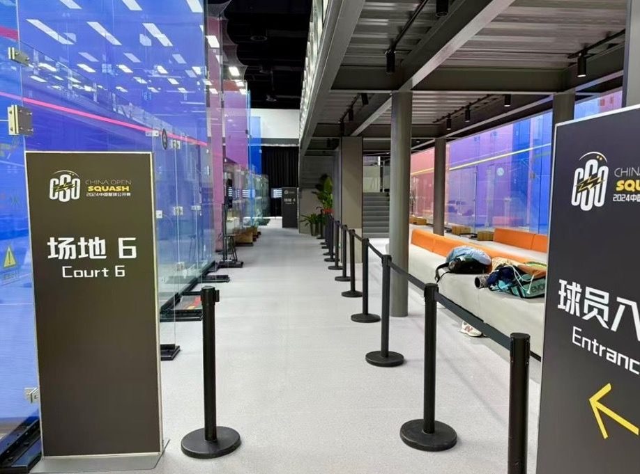 Row of glass courts along the venue concourse, Court 6 signage